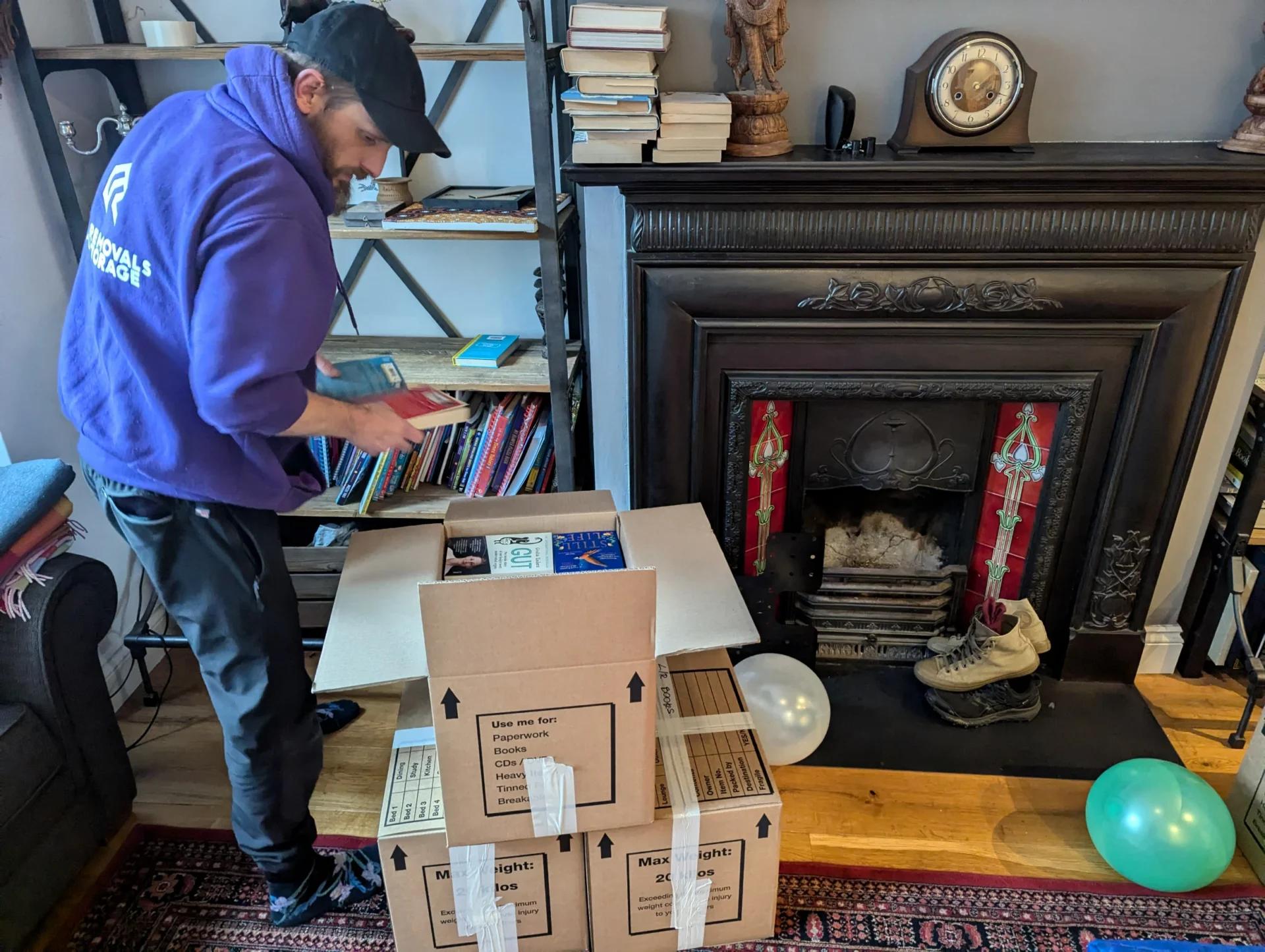 RAD Removals team member carefully packing books into small moving boxes in a bright West London home